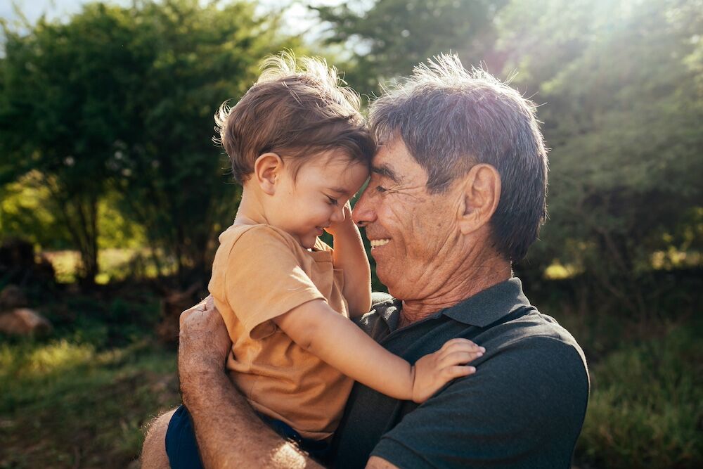 A senior man hugs his grandson as they visit at a dementia care community