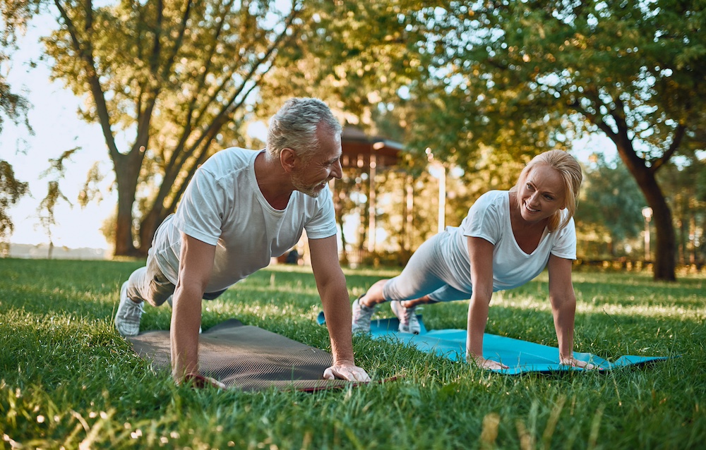 A senior couple doing yoga in the park outdoors