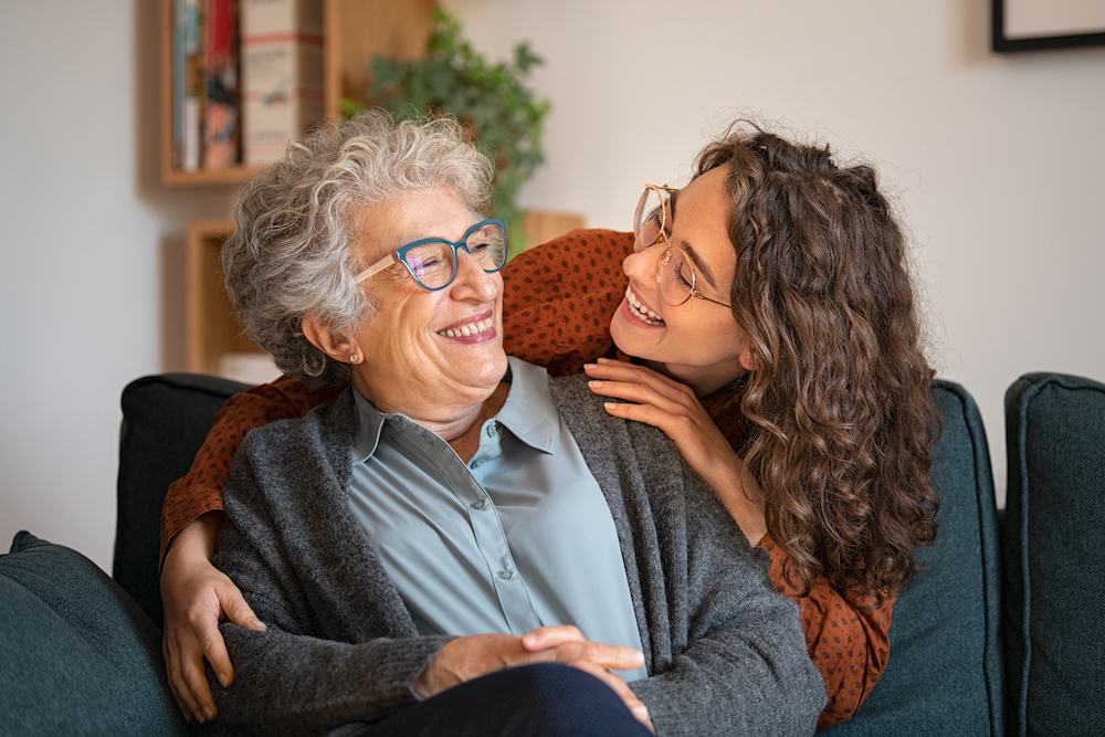 A senior woman and her daughter hug and laugh together