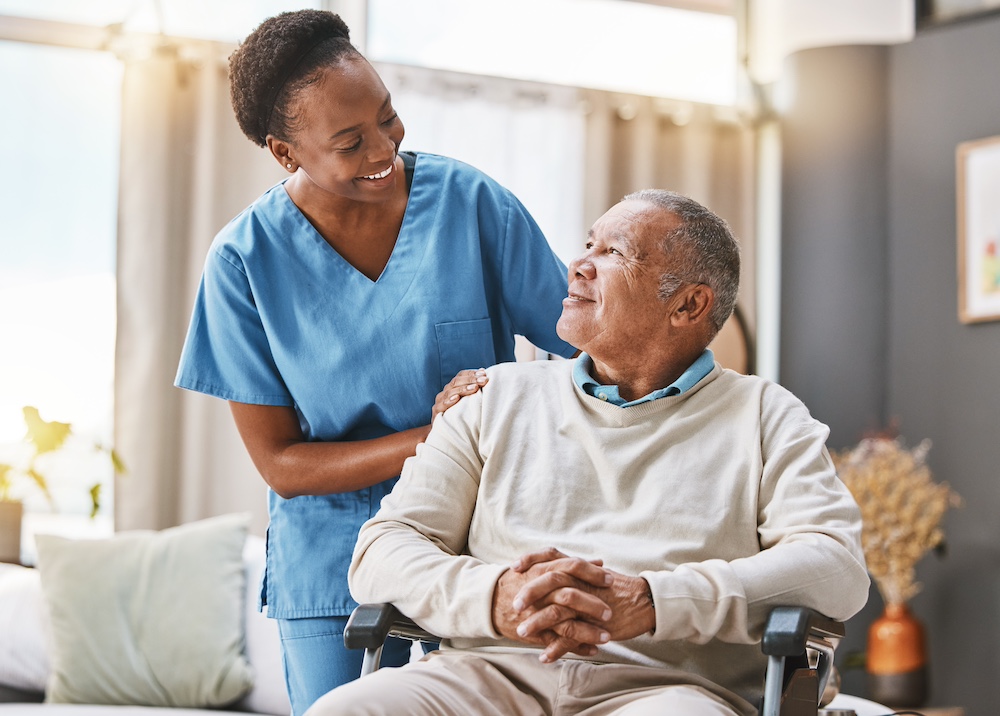 A senior man and his caregiver smile and talk together