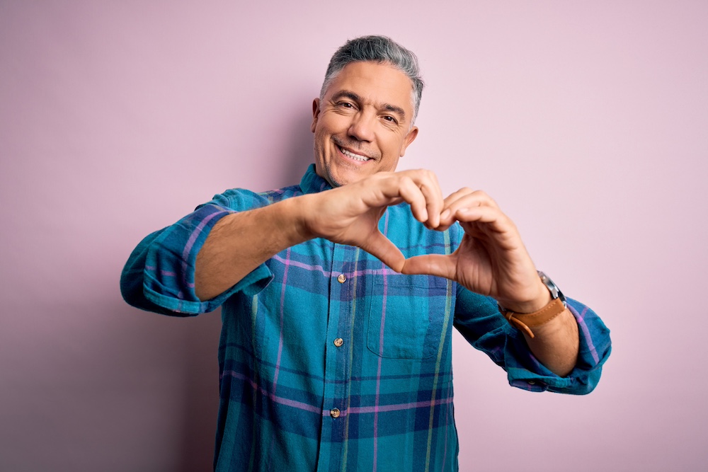 A senior man making a heart shape with his hands