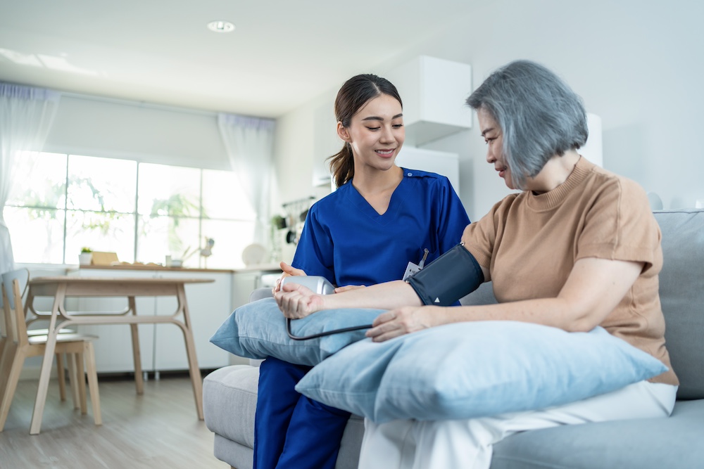 A resident of senior memory care community having her blood pressure checked by a nurse