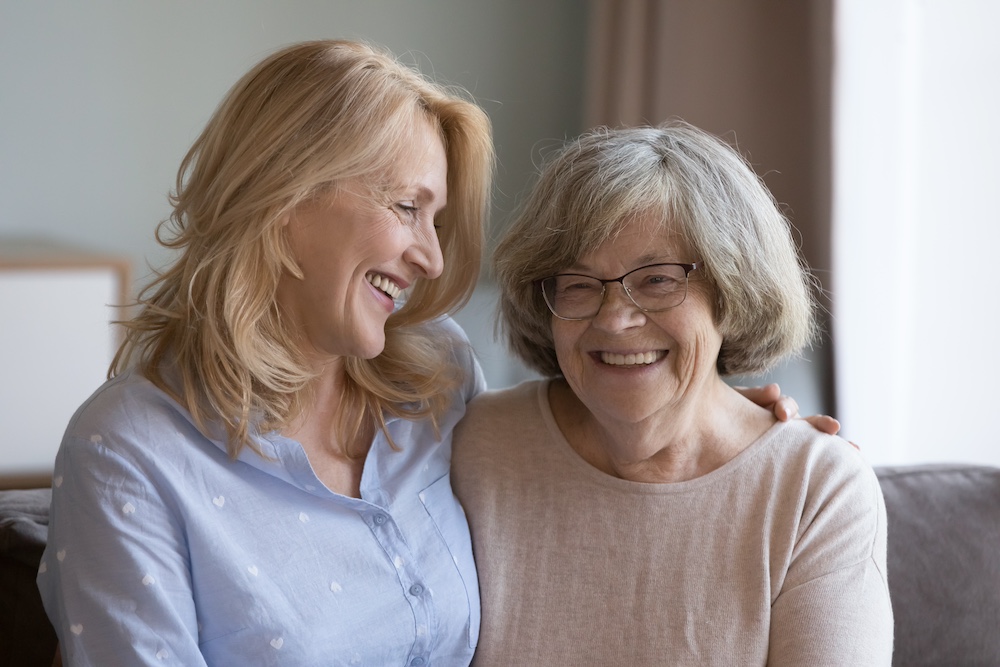 A senior woman laughs as her daughter visits her at one of the best memory care communities