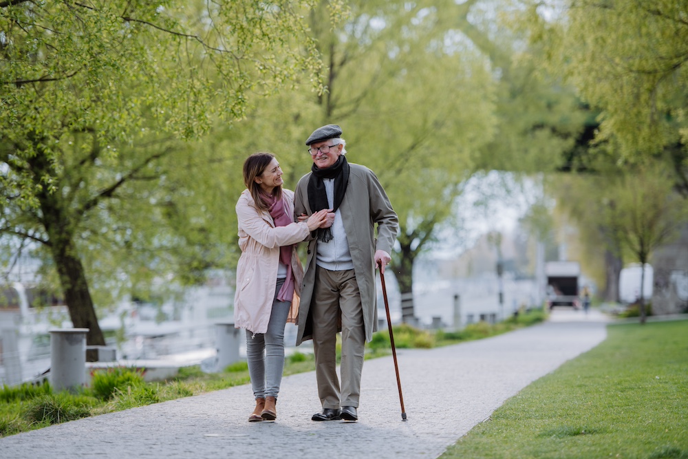 A senior man and his adult daughter go for a walk around the best senior care community near me