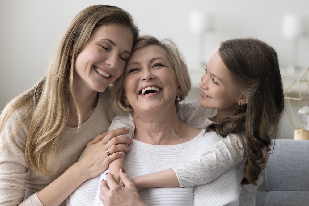 A senior woman hugs her daughter and grand daughter