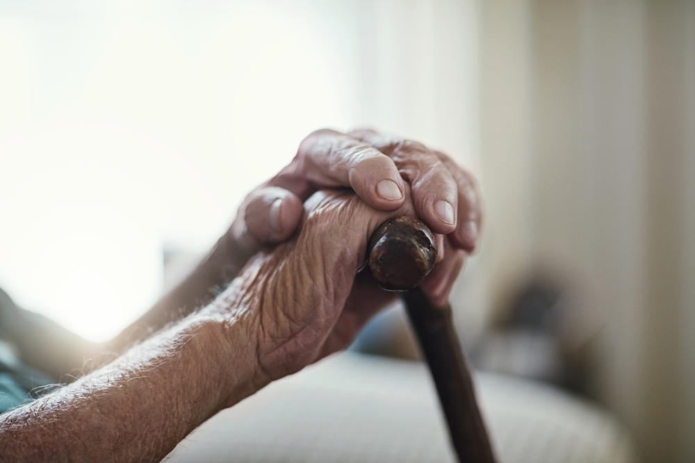 Hands on cane in dementia care community.