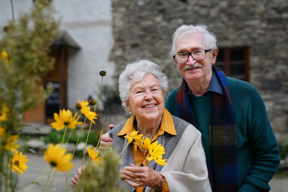 Happy senior couple posing with the flowers at the best memory care communities