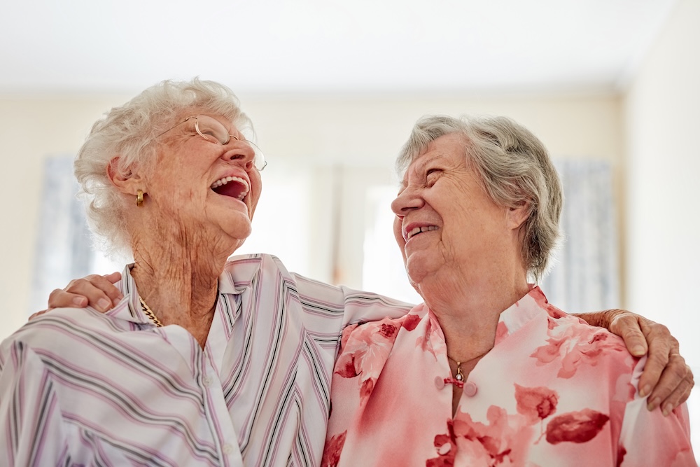 Two senior women laughing together and enjoying our dementia care community